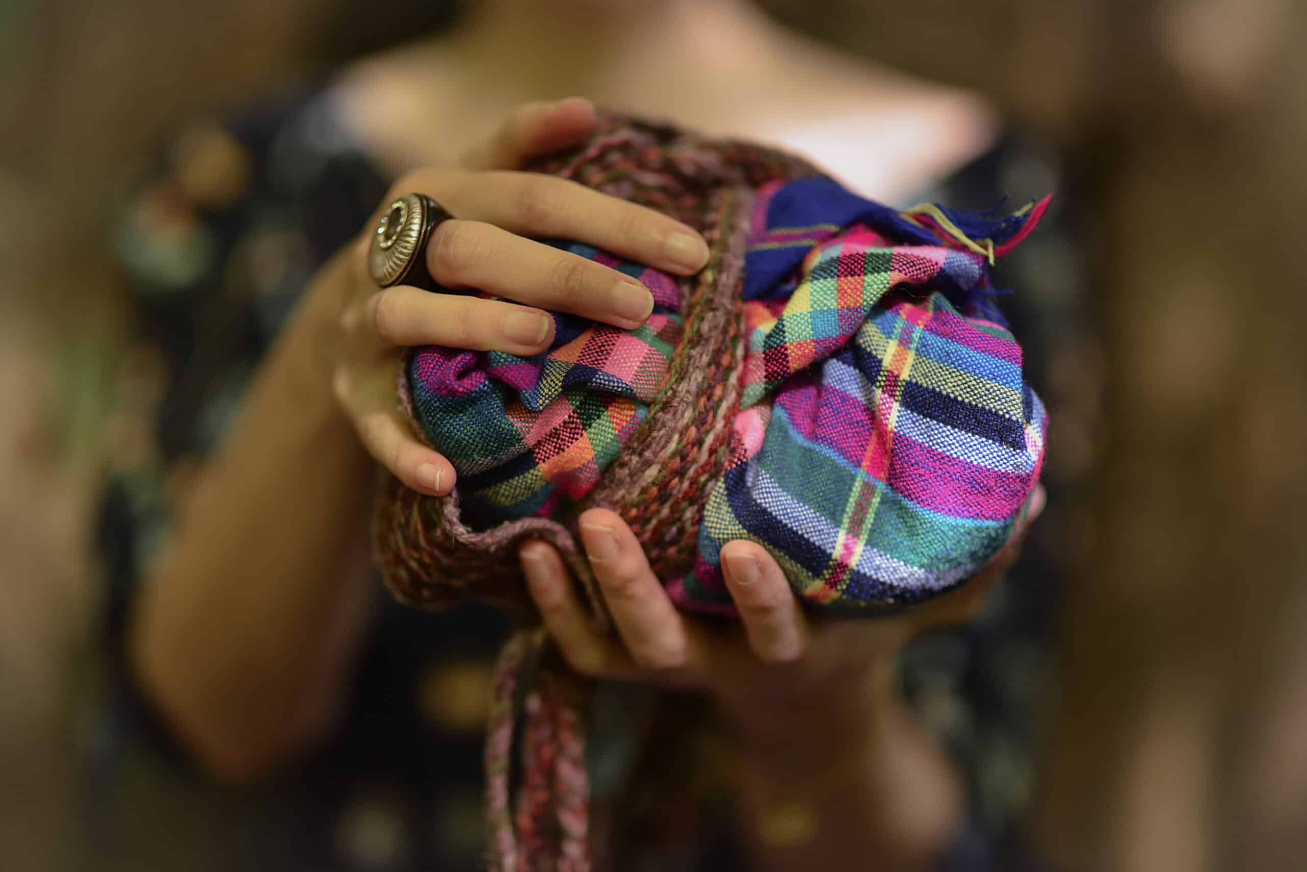 A woman holding a colorful scarf in her hands.