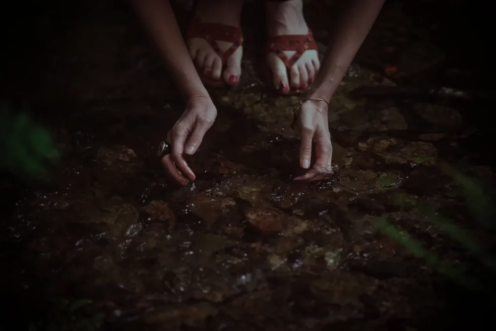 A woman's feet immersed in a stream of water, experiencing the soothing effects of Reiki Healing.