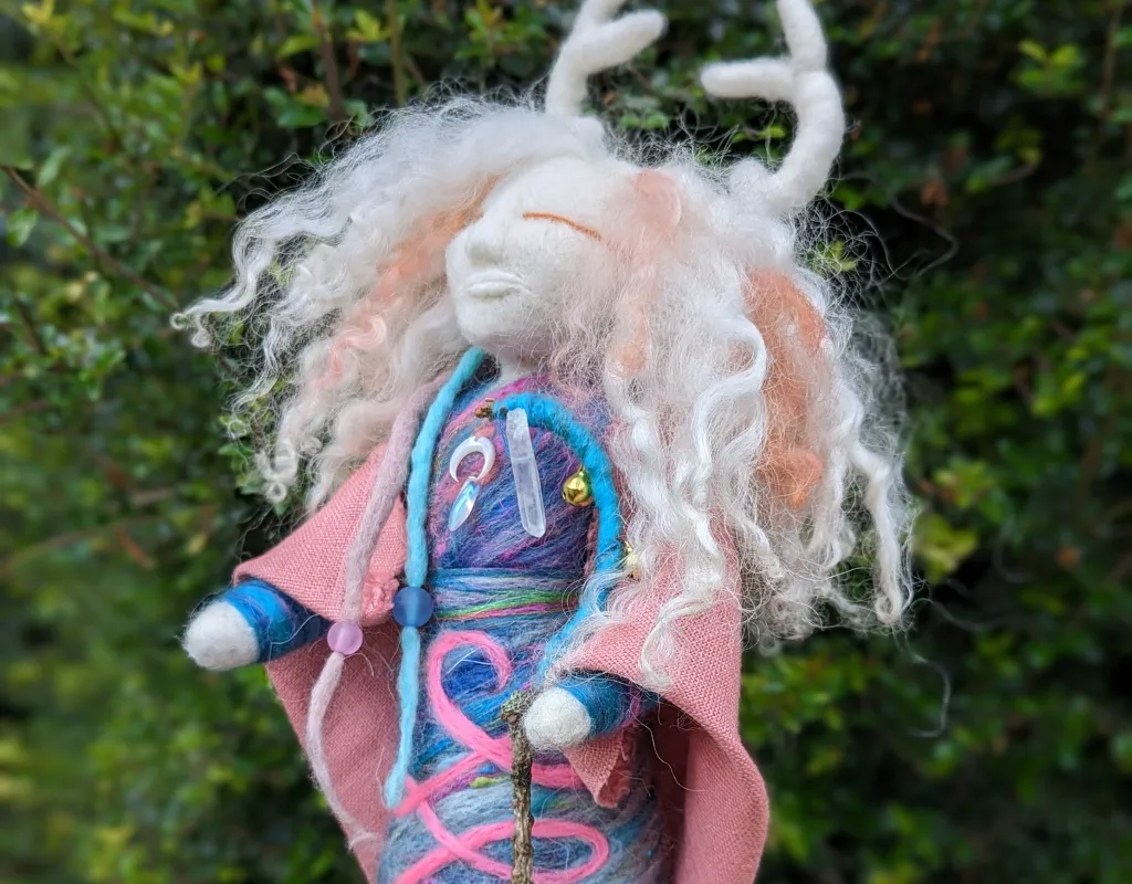 A doll with long hair and a pink cloak that provides Reiki Healing.